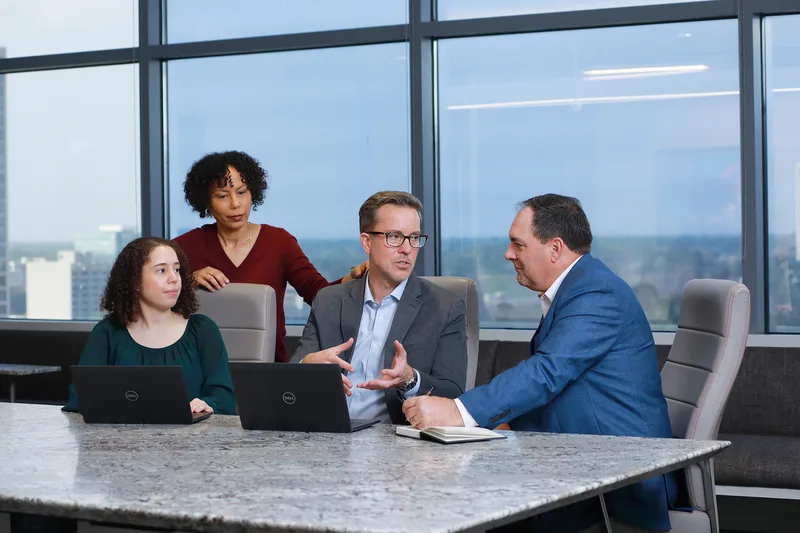 Corporate lifestyle conference room session professionals collaborating over Dell laptops