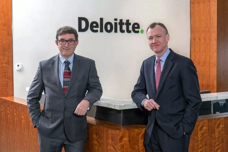 Two executives posing for corporate headshots at Deloitte reception desk