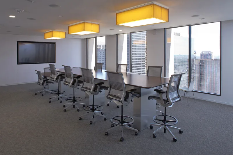 Corporate boardroom with yellow box pendants drafting chairs and high-rise windows