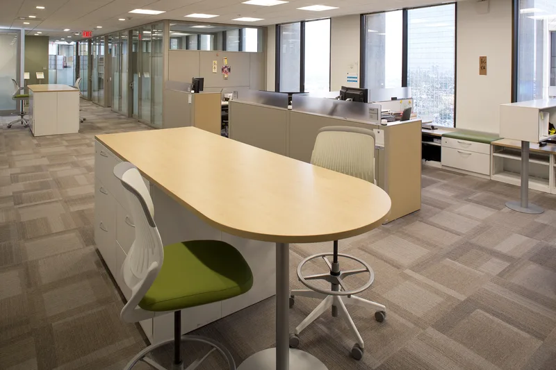 Corporate collaboration standing table with green upholstered stools in modern office