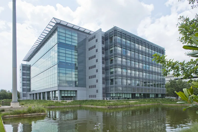 glass curtain wall executive office building reflected in landscaped corporate pond