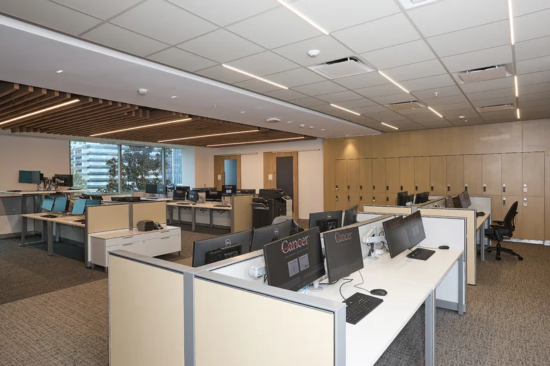 Open-plan corporate office with cubicle workstations, Dell monitors, and wood locker wall
