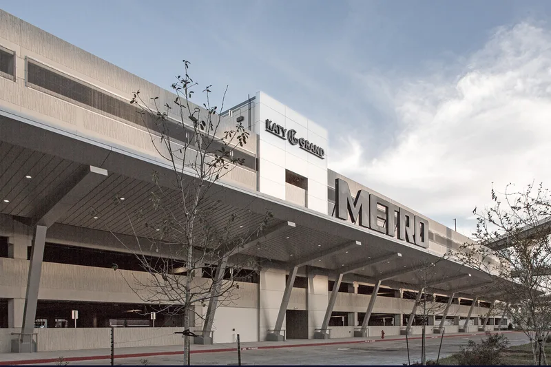 Multi-level commercial building exterior with steel-panel facade and illuminated canopy overhang
