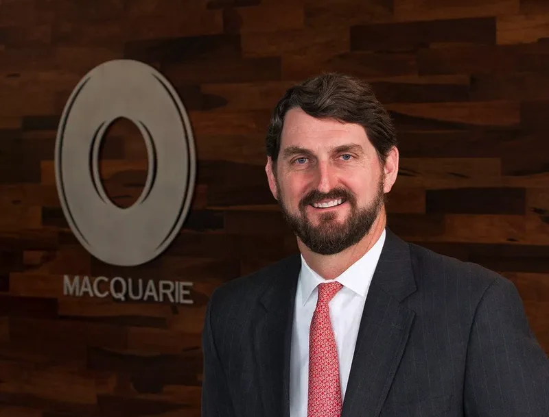 Executive portrait bearded man in charcoal suit and red tie wood-paneled office