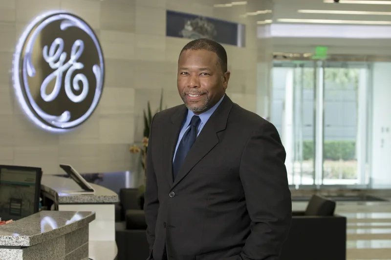 GE corporate headshot professional man dark suit blue tie lobby