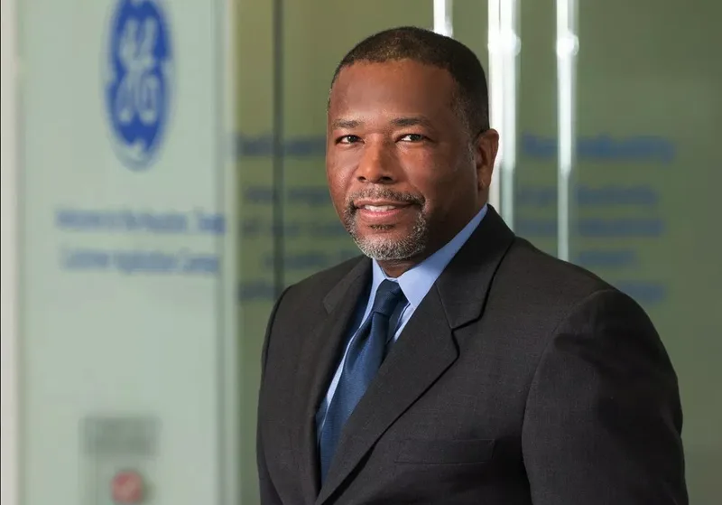 Executive corporate headshot professional man dark suit glass office backdrop