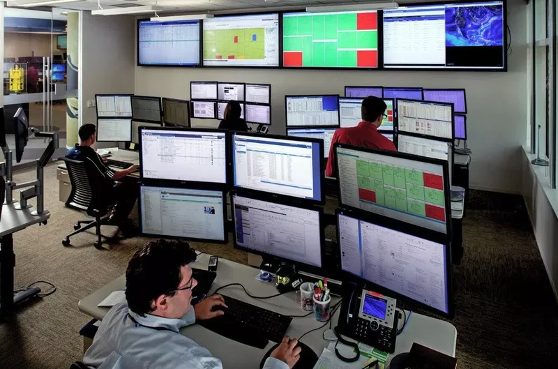 corporate professionals working multi-monitor workstations in operations control room