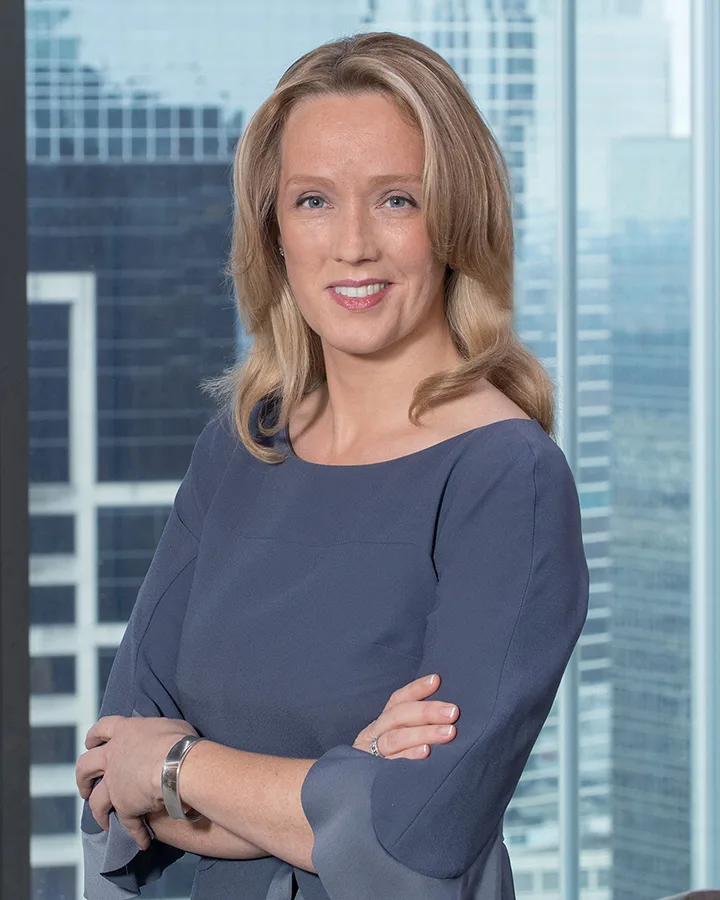 On site headshots woman gray blouse arms crossed glass tower backdrop