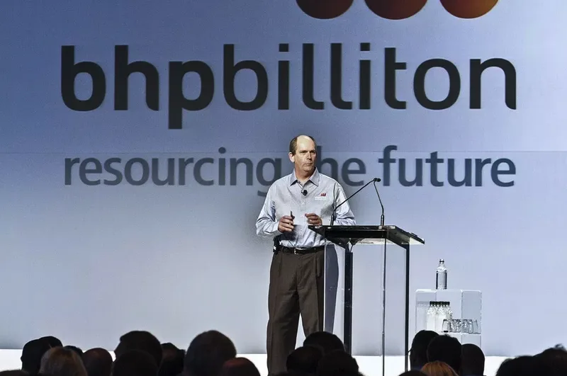 Executive speaker at glass podium with branded corporate stage backdrop
