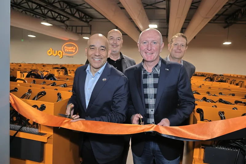 Four executives cutting orange ribbon at corporate technology facility grand opening