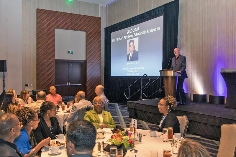ILA scholarship awards banquet speaker at podium presenting to formally seated guests