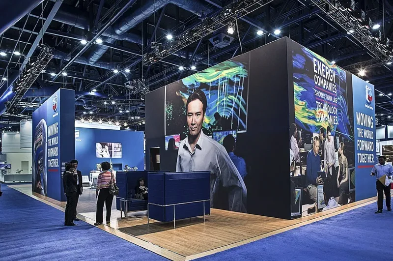 Corporate trade show exhibit with LED video walls and branded blue seating