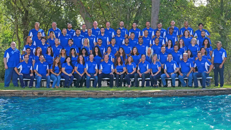 Corporate group portrait matching royal blue polos outdoor poolside setting