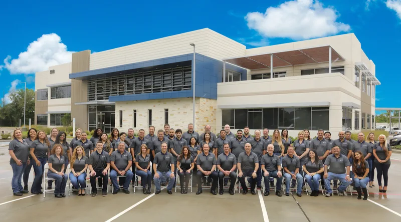 corporate group portrait large team matching polo shirts modern office building