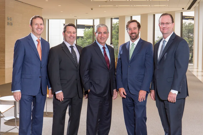 Moelis Ken group five executives navy pinstripe suits corporate atrium