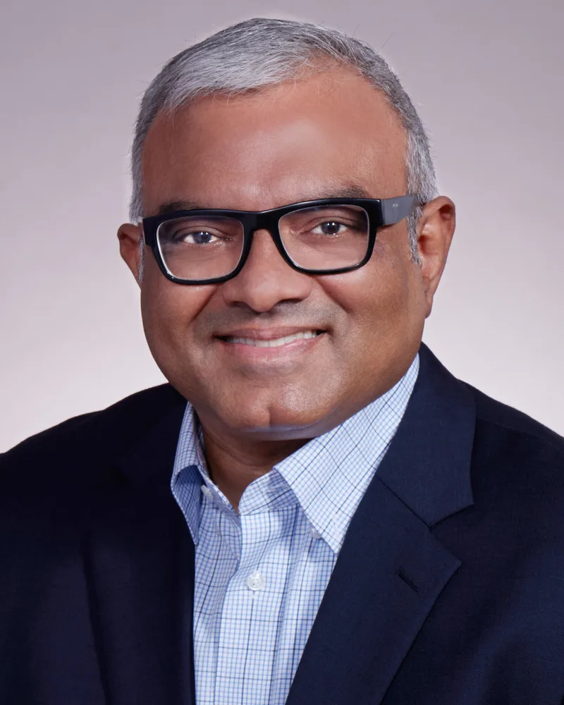 Corporate headshot executive man glasses navy blazer neutral studio background