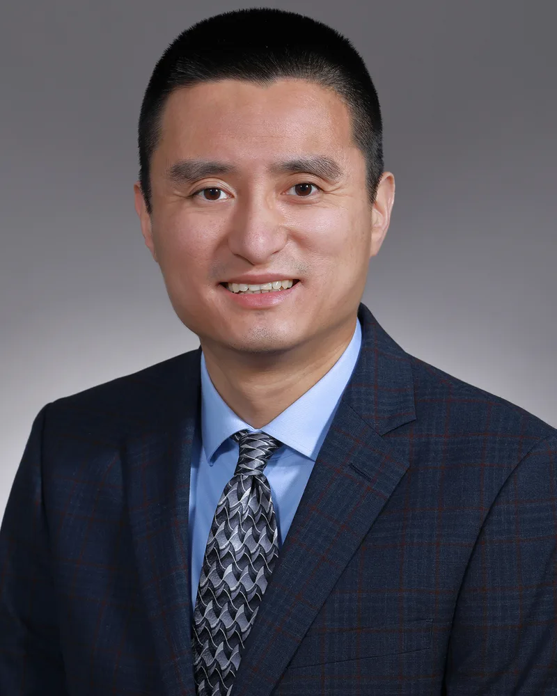 Professional male corporate headshot in navy plaid blazer and gray tie