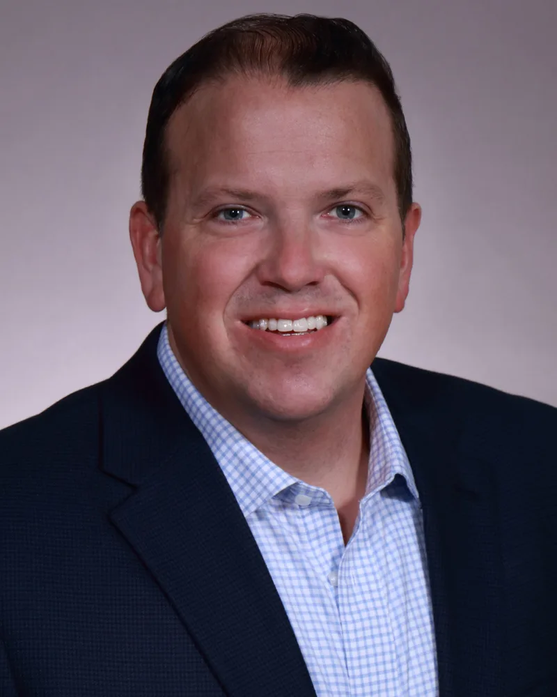professional corporate headshot smiling man navy blazer light blue gingham shirt