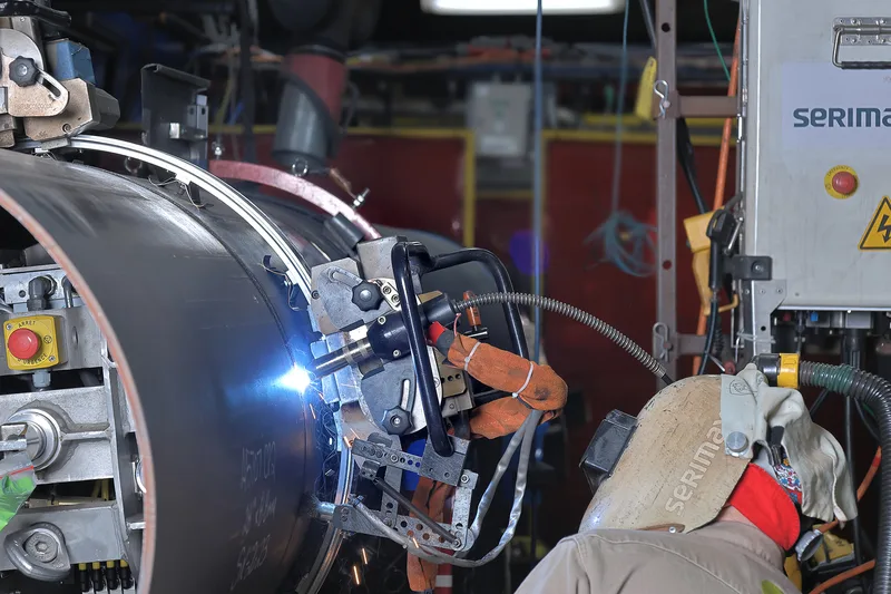 automatic pipe welding station technician joining large diameter black steel pipeline