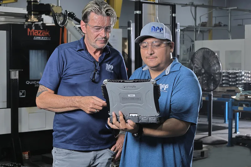 Two men consulting Panasonic Toughbook rugged tablet inside Mazak CNC manufacturing facility