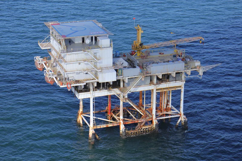 Aerial view of offshore oil platform rising above open ocean waters