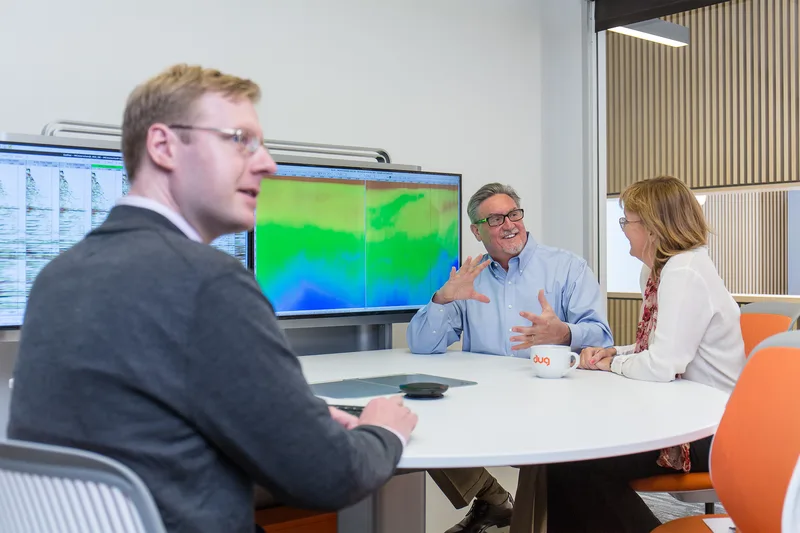Corporate lifestyle meeting executives discussing vivid geological seismic visualization screens