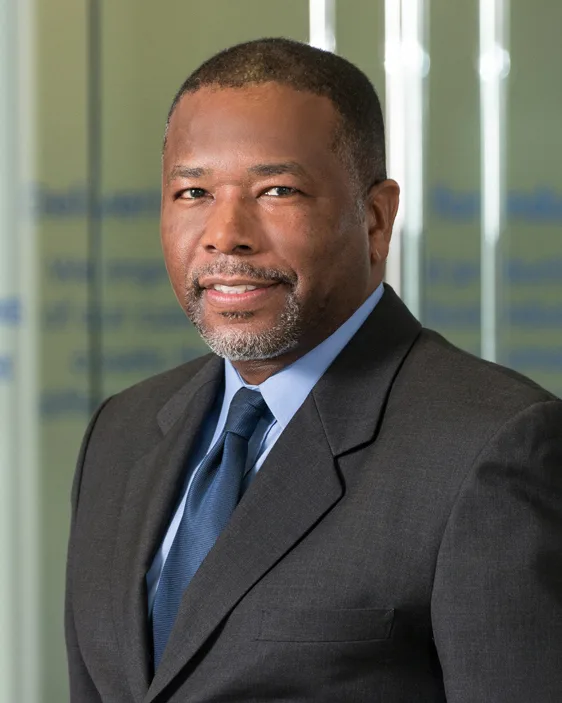 GE Power executive portrait charcoal suit blue tie professional glass office background